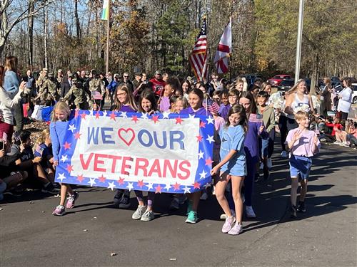 Kids marching with banner that reads We Love Our Veterans